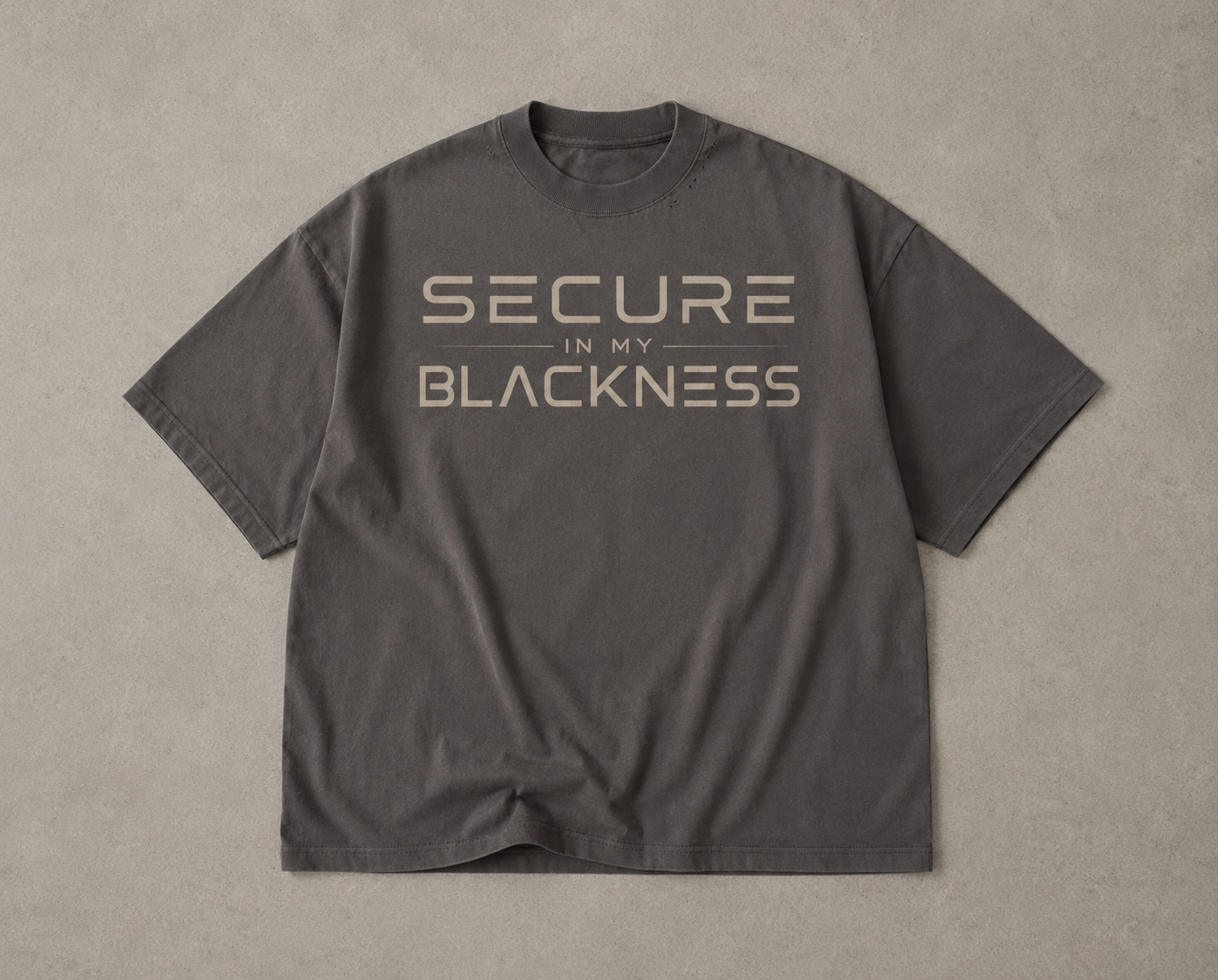 Gray t-shirt with 'Secure in my Blackness' text on a beige background