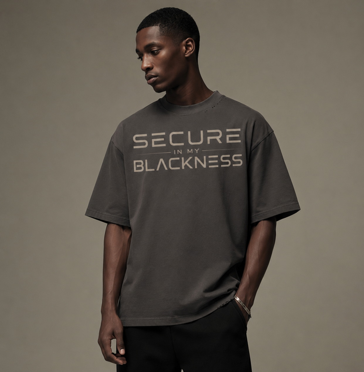 Man wearing a gray t-shirt with 'Secure in My Blackness' text on a brown background